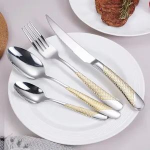Détail de coutellerie en acier inoxydable, poignée texturée dorée élégante, art de la table.