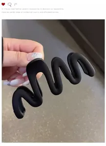 Detail view of black wave hair claw clip, matte texture design for elegant bun styling.