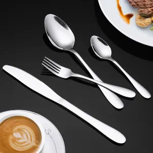 Dettaglio set di posate in acciaio inox con coltello forchetta e cucchiai sul tavolo.