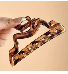 Primo piano dettagliato della grande molletta per capelli tartarugata con design geometrico e molla.