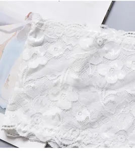 Primer plano detalle top banda de encaje blanco, textura de tela de malla floral.