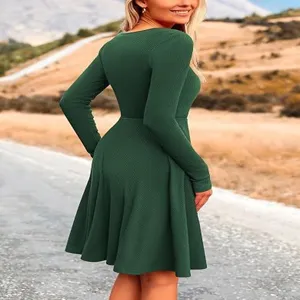 Detailed view of the dark green long-sleeve ribbed midi dress worn outdoors by model.