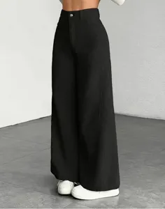 Gedetailleerde close-up van zwarte dames broek met hoge taille en corduroy wijde pijpen.