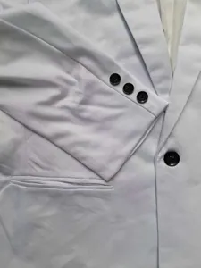 Primo piano dettaglio del polsino della giacca da abito bianca da uomo con bottoni neri.