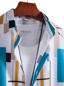 Close-up detail of mens geometric print short sleeve shirt layered with white t-shirt.