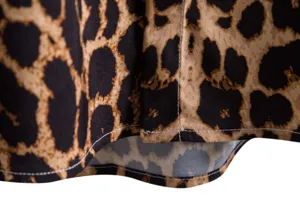 Vista de cerca del tejido de la camisa de leopardo con costuras blancas limpias.