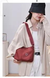 Casual stylish red shoulder bag with wide strap and chic round logo detail for women daily.