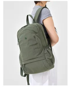 Casual green nylon travel backpack on model back showing side design and shoulder straps.