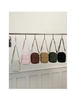 Detail view of multiple colored mini crossbody phone bags hanging neatly on a metal display rod.