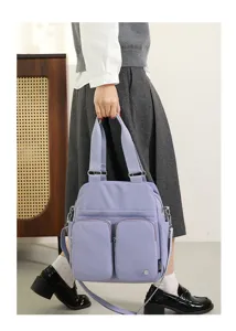 Detailed view of the multi-pocket nylon shoulder bag in light purple, showing side carry style.