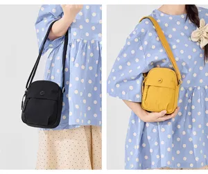 Detailed view of lightweight nylon crossbody bag with front zipper pocket and strap.