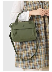 Olive green nylon crossbody bag detail, featuring dual top handles and adjustable strap.