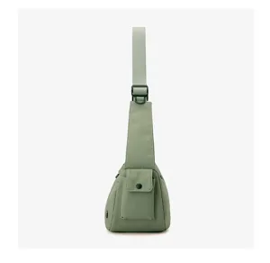 Detail view of the sage green nylon crossbody sling bag showing front pocket and wide strap.