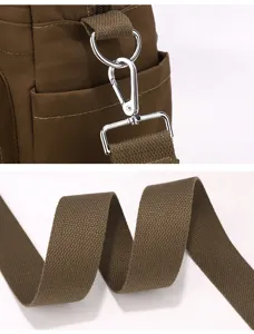 Nylon crossbody bag detail, brown shoulder strap and metal hardware closeup view.