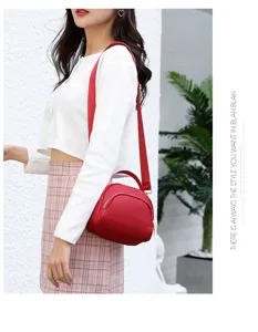Red canvas crossbody bag detail shot, compact shoulder handbag with zipper and top handle.