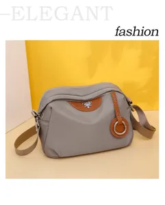 Detailed view of casual nylon crossbody bag with brown leather trim and metal ring ornament.