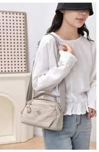 Detail view of lightweight nylon casual crossbody bag with multi layers and wide strap.