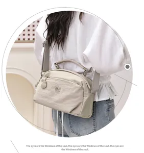 Detail view of light grey casual crossbody bag with multiple zipper compartments and shoulder strap.