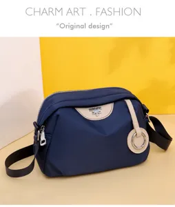 Detailed view of casual blue oxford cloth crossbody bag with stylish beige trim and metal ring.
