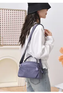 Detail shot of the stylish purple crossbody bag worn by a model, showing multi-layer casual design.