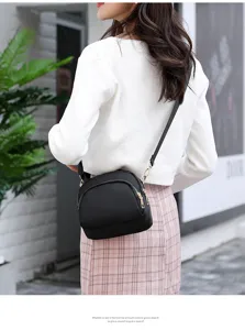 Black nylon crossbody shoulder bag detail view with metal zippers and adjustable strap.