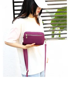Detail view of the purple nylon crossbody bag, showing fine zipper and durable strap design.