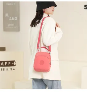 Pink oxford cloth crossbody bag detail showing shoulder strap, front pocket and zipper.