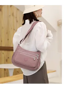 Detail view of the multi-pocket nylon crossbody shoulder bag in mauve pink, showing layered zippers.