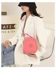 Pink nylon multi-purpose crossbody bag worn by model, detail view showing strap and pocket
