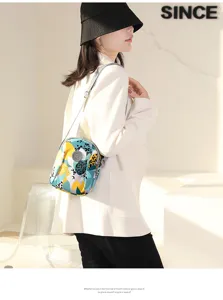 Detailed view of the colorful printed nylon crossbody mini bag worn by model indoors.