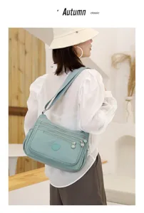 Detailed view of light green multi-pocket nylon crossbody shoulder bag in lifestyle.