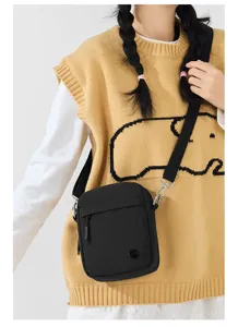 Close-up view of a black crossbody phone bag with zipper pocket and shoulder strap detail.