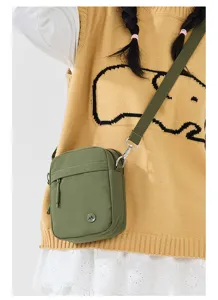 Green canvas crossbody shoulder bag detail, casual minimalist style small square phone bag.
