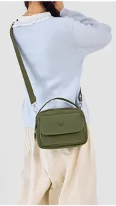 Detailed view of the olive green nylon crossbody bag showcasing front pocket and handle.