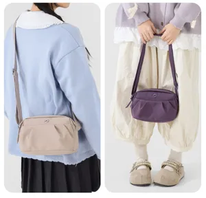 Close-up detail of multi-layer oxford cloth crossbody bag worn by models in daily style.
