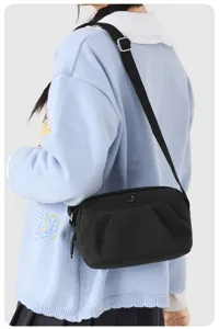 Detailed view of black nylon crossbody bag worn by model, showing strap and front pocket.