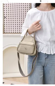 Gros plan détaillé du sac bandoulière en nylon décontracté avec poche avant et sangle.