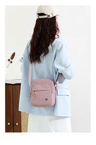 Detail view of the stylish pink nylon crossbody bag worn on shoulder, lightweight and convenient.