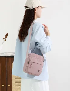Detailed view of a minimalist pink crossbody bag worn by model showing its practical design.