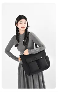 Detail view of black nylon tote bag with front pockets, worn by model for daily commute.