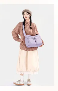 Detailed shot of a large-capacity purple nylon shoulder bag worn by a model in a studio setup.
