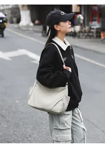 Detail view of the lightweight nylon shoulder bag worn by model outdoors, casual style.