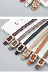 Detailed shot of women's thin leather belt featuring an elegant pearl rhinestone rectangular buckle.