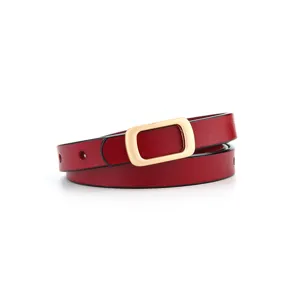 Detail shot of red thin leather belt with gold rectangular metal buckle, elegant and stylish.