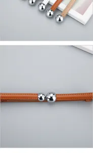 Gros plan sur une ceinture fine en cuir pour femme avec une boucle ronde en métal.