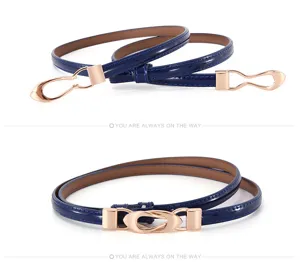 Gros plan sur la fine ceinture en cuir vernis bleu marine avec boucle métallique or rose.
