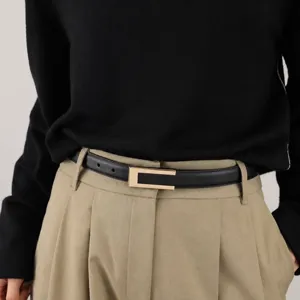 Detailopname van een zwarte leren damesriem met een stijlvolle metalen gesp gedragen op een broek.