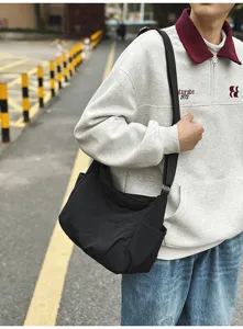 Close-up of black nylon crossbody bag, showing adjustable strap and durable fabric details.