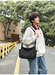 Casual black nylon shoulder bag shown in an outdoor street scene, lightweight and spacious.