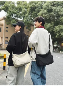 Outdoor street lifestyle detail shot showing casual nylon crossbody bag on models in daily use.